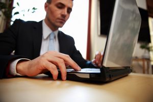Businessman working on a laptop undertaking 7 steps for promoting a blog